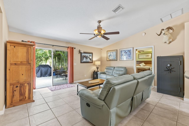 living area with a ceiling fan, lofted ceiling, visible vents, and light tile patterned floors