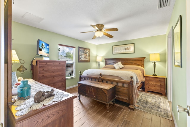 bedroom with a ceiling fan, wood finished floors, visible vents, and baseboards