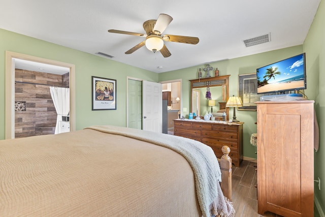 bedroom featuring wood tiled floor, visible vents, ceiling fan, and ensuite bathroom