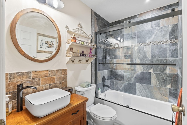 full bathroom featuring combined bath / shower with glass door, a sink, and toilet