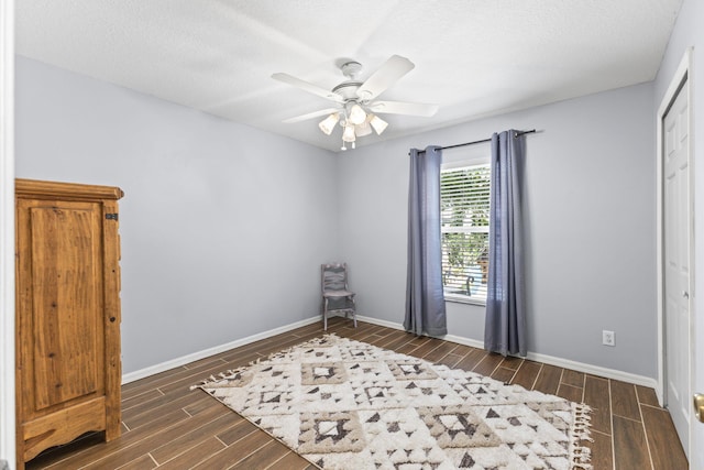 unfurnished room with wood tiled floor, ceiling fan, a textured ceiling, and baseboards