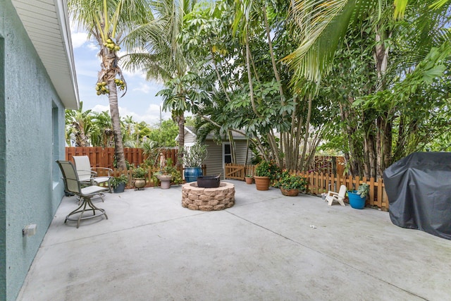 view of patio with an outdoor fire pit, fence, and a grill