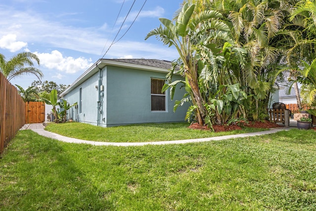 view of home's exterior featuring stucco siding, a lawn, and fence