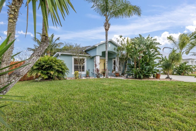 view of front of property featuring a front yard, fence, and stucco siding