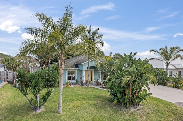 view of front facade featuring concrete driveway, a front yard, fence, and stucco siding