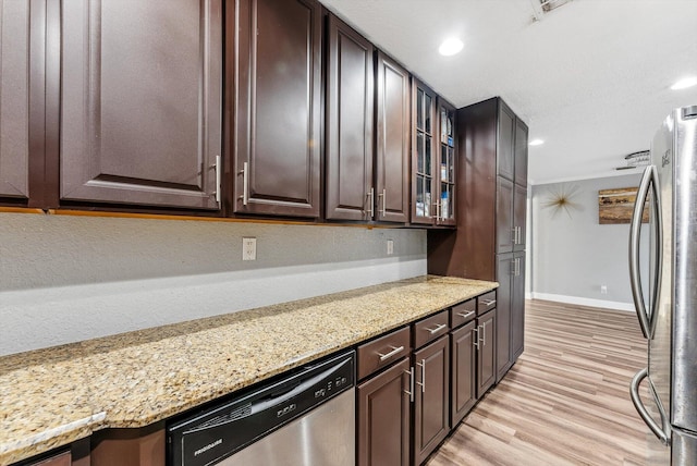 kitchen with light stone counters, appliances with stainless steel finishes, dark brown cabinetry, and light wood-style floors