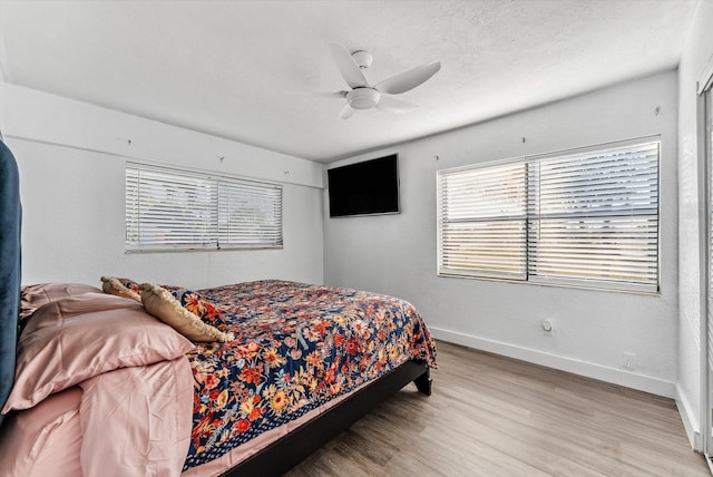 bedroom with light wood-type flooring, a ceiling fan, baseboards, and a textured ceiling