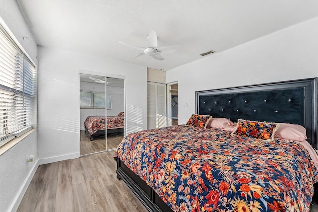 bedroom featuring ceiling fan, wood finished floors, visible vents, baseboards, and a closet