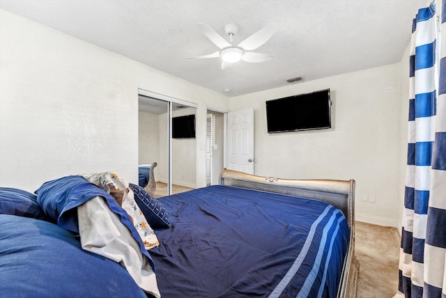 bedroom featuring visible vents, ceiling fan, carpet, a textured ceiling, and a closet