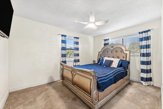 carpeted bedroom featuring a ceiling fan, baseboards, and a textured ceiling