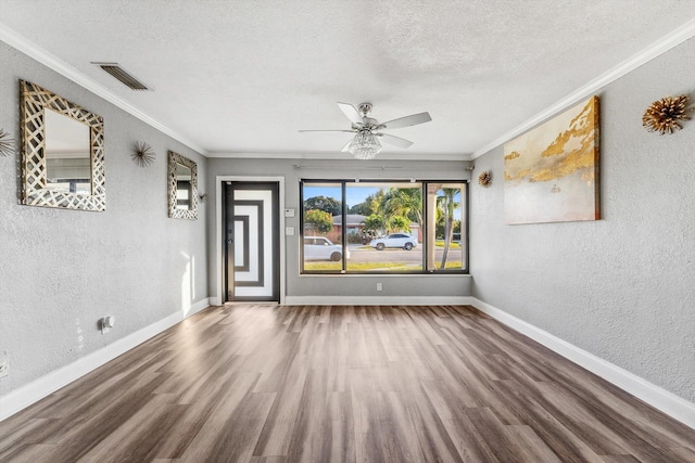 unfurnished room with baseboards, visible vents, wood finished floors, and a textured wall