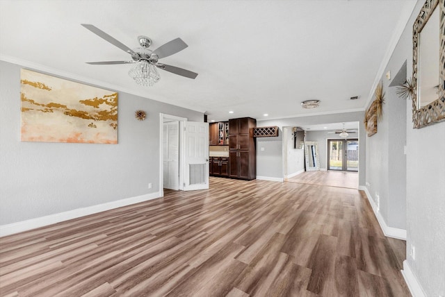 unfurnished living room featuring ceiling fan, ornamental molding, wood finished floors, and baseboards