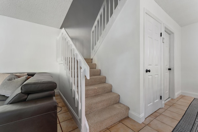 stairs featuring tile patterned flooring, baseboards, and a textured ceiling