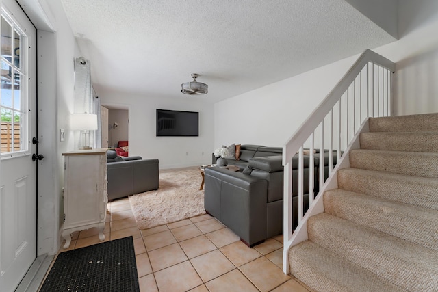 living room with stairway, a textured ceiling, and light tile patterned floors