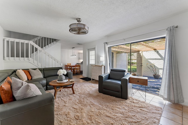 living room featuring stairs, a textured ceiling, tile patterned flooring, and visible vents