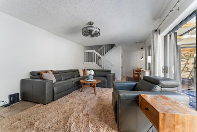 tiled living area featuring visible vents, a textured ceiling, and stairs