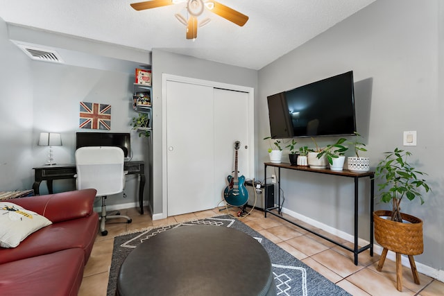 tiled living area with a ceiling fan, visible vents, a textured ceiling, and baseboards