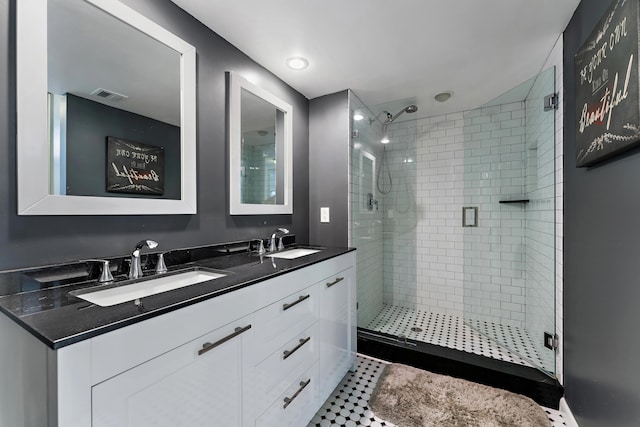 bathroom featuring visible vents, a sink, a shower stall, and double vanity