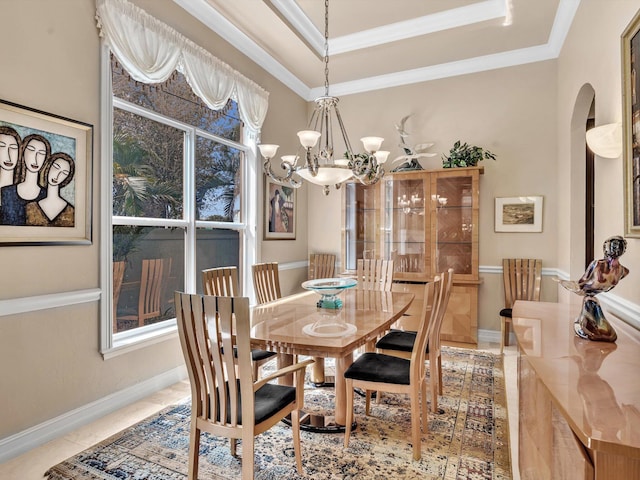 dining space with arched walkways, a raised ceiling, an inviting chandelier, and ornamental molding