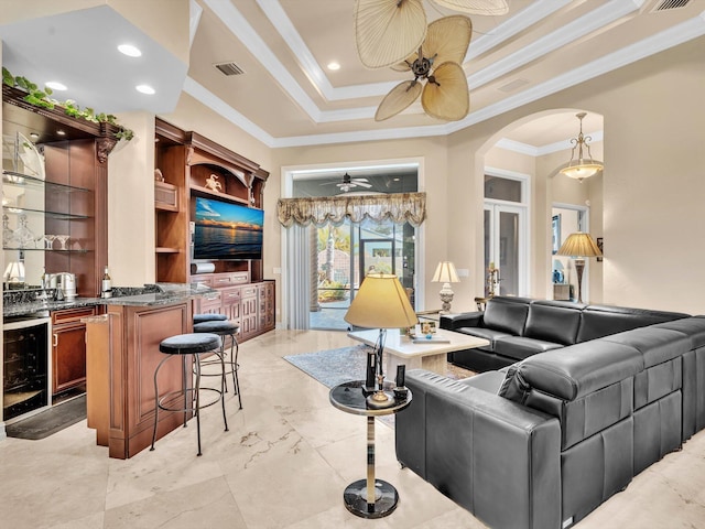 living room with visible vents, beverage cooler, a ceiling fan, ornamental molding, and arched walkways