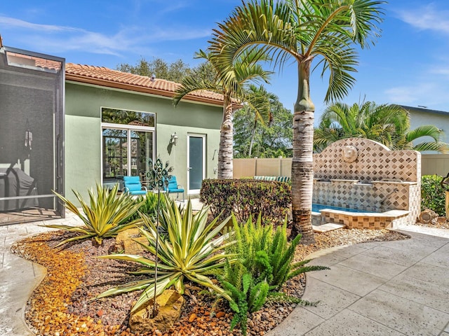 exterior space featuring stucco siding, a tile roof, and fence