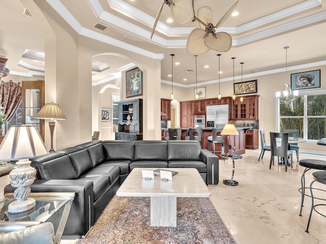 living area featuring a ceiling fan, visible vents, a tray ceiling, arched walkways, and ornamental molding