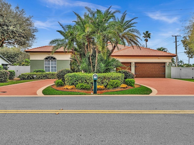 mediterranean / spanish-style home with concrete driveway, a tiled roof, a gate, and stucco siding