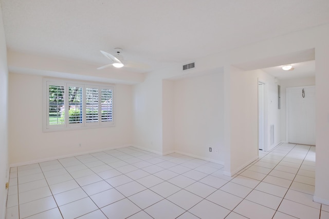 empty room featuring a ceiling fan, light tile patterned flooring, visible vents, and baseboards