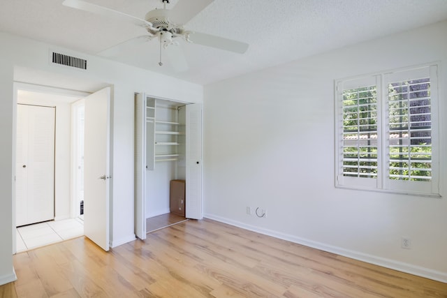 unfurnished bedroom featuring visible vents, a ceiling fan, wood finished floors, a textured ceiling, and a closet