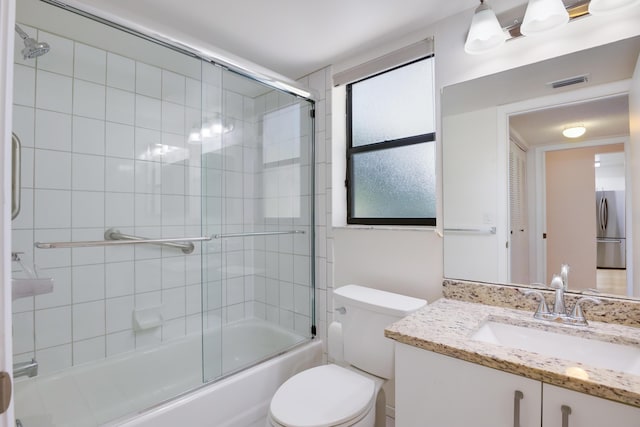 bathroom featuring toilet, vanity, visible vents, and enclosed tub / shower combo