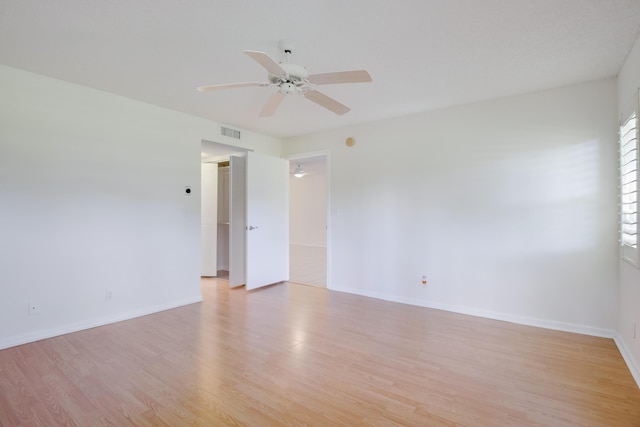 unfurnished room featuring a ceiling fan, light wood-style flooring, visible vents, and baseboards