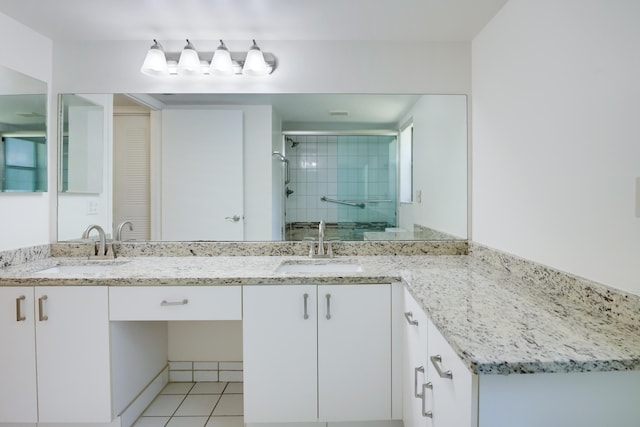 bathroom featuring double vanity, a stall shower, a sink, and tile patterned floors