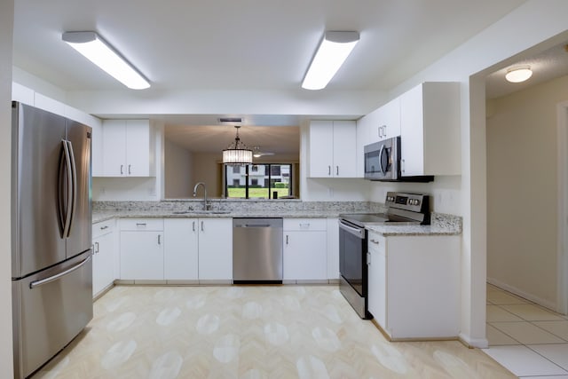 kitchen featuring light stone counters, appliances with stainless steel finishes, white cabinets, and a sink