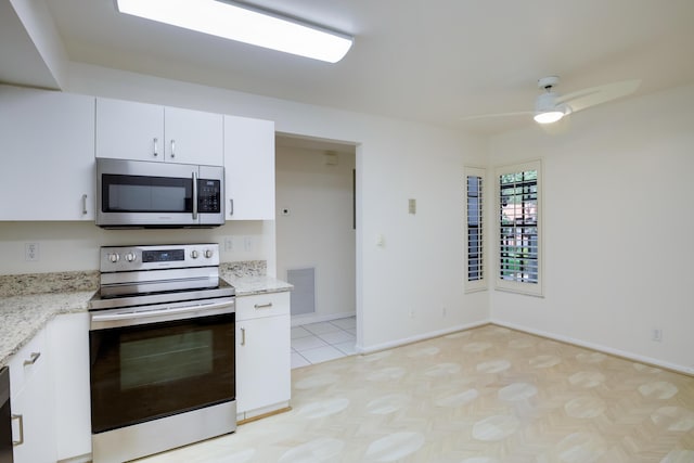 kitchen featuring visible vents, a ceiling fan, appliances with stainless steel finishes, light stone countertops, and white cabinetry