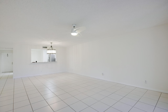 empty room featuring light tile patterned floors, baseboards, and ceiling fan with notable chandelier