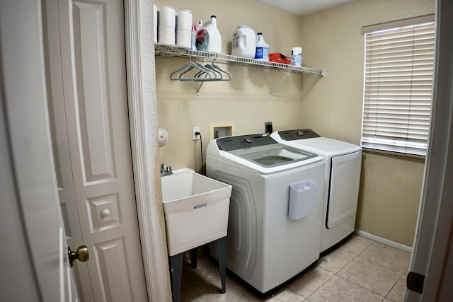 washroom featuring light tile patterned floors, a sink, washer and dryer, laundry area, and baseboards