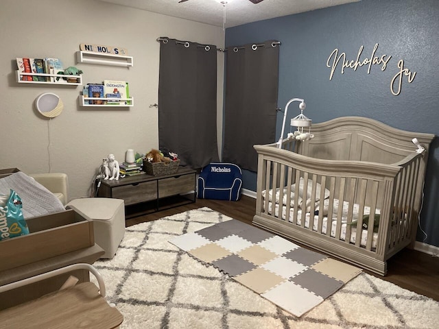 bedroom with a crib, wood finished floors, and baseboards