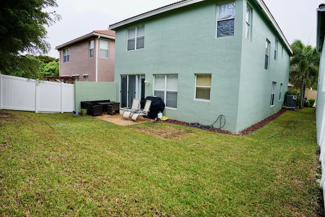 back of house featuring central AC, a yard, fence, and stucco siding