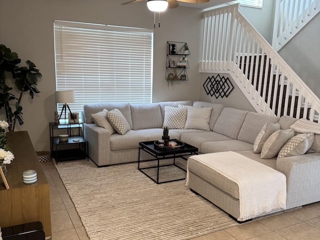 living room with light tile patterned floors, stairs, and a ceiling fan