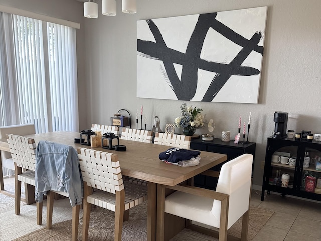 dining space with a textured wall and light tile patterned flooring