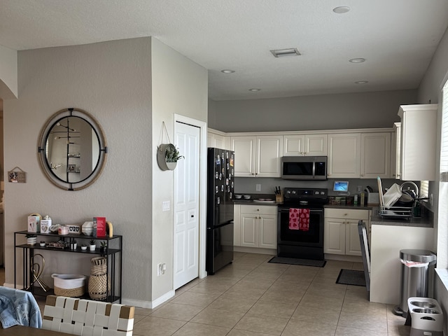 kitchen featuring light tile patterned floors, baseboards, white cabinets, black appliances, and dark countertops