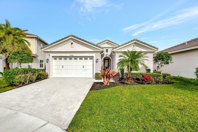 ranch-style home featuring an attached garage, a tiled roof, decorative driveway, stucco siding, and a front yard