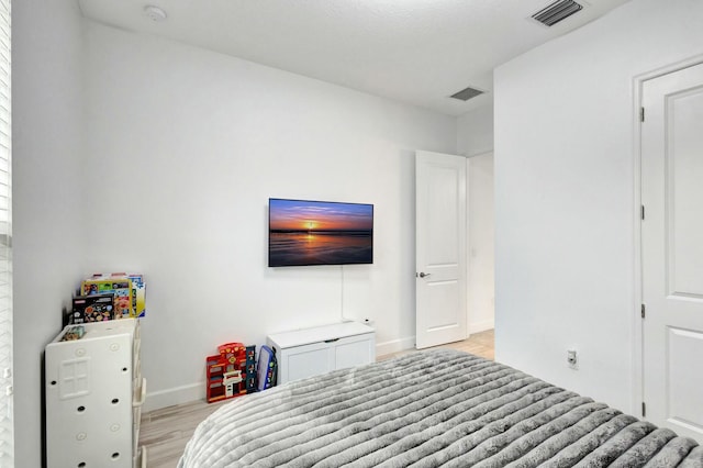 bedroom with light wood-type flooring, visible vents, and baseboards