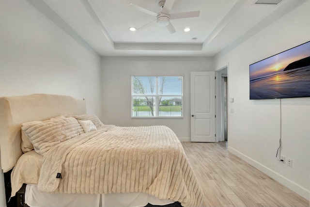 bedroom featuring baseboards, ceiling fan, a tray ceiling, light wood-type flooring, and recessed lighting