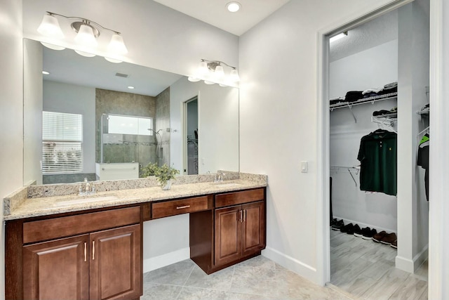 bathroom with double vanity, visible vents, a spacious closet, a stall shower, and a sink