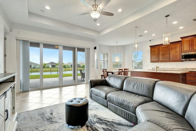 living room featuring recessed lighting, light tile patterned flooring, and a tray ceiling