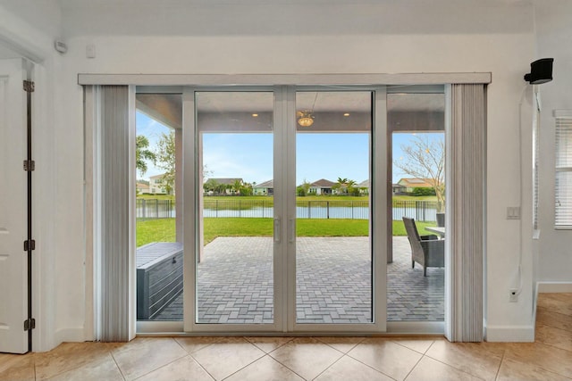 doorway to outside with a water view, baseboards, and tile patterned floors