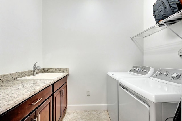 washroom featuring light tile patterned flooring, a sink, baseboards, washer and dryer, and cabinet space