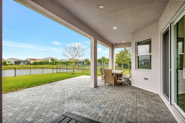 view of patio / terrace featuring outdoor dining area, a water view, and a fenced backyard