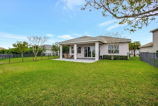 rear view of house featuring a lawn, a patio area, a fenced backyard, and stucco siding